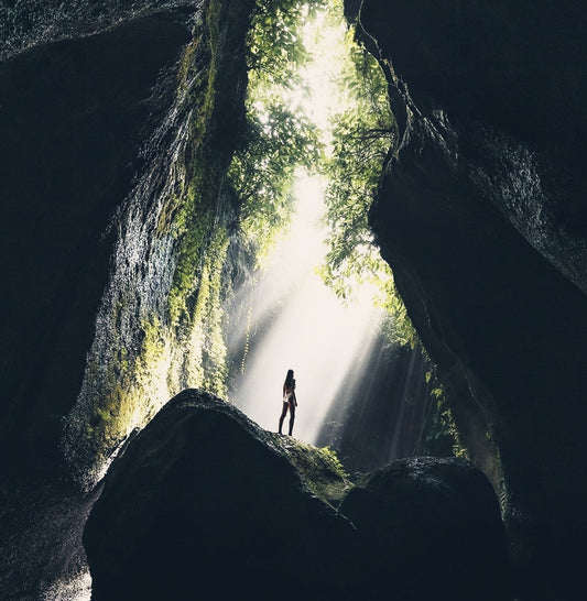 woman standing on rock with light beaming down